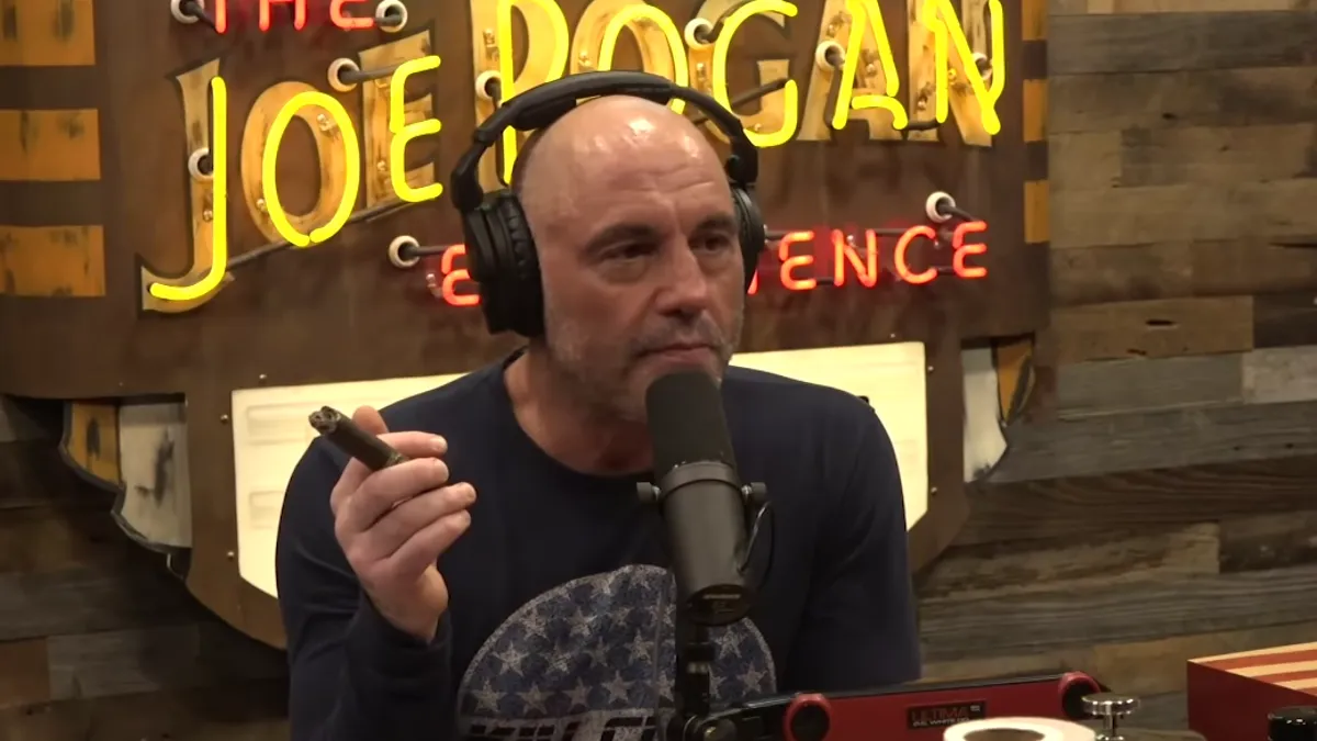 Joe Rogan holding a cigar on his podcast show.